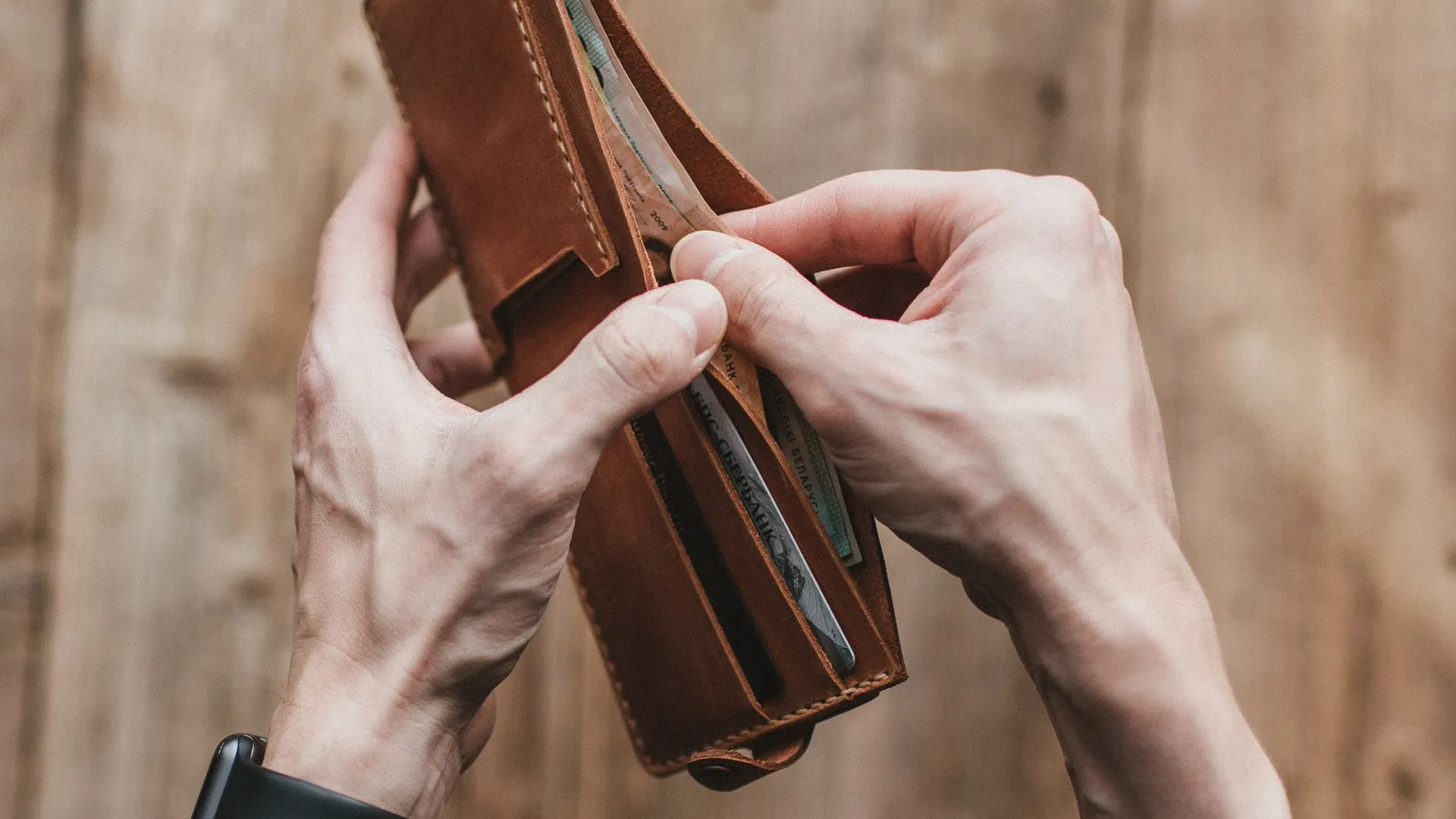 Männderhände halten ein Portemonnaie mit Geldscheinen drin